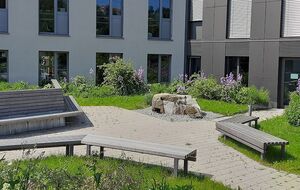 Begrünter Innenhof mit Sitzbänken, Staudenpflanzung und gepflasterten Wegen